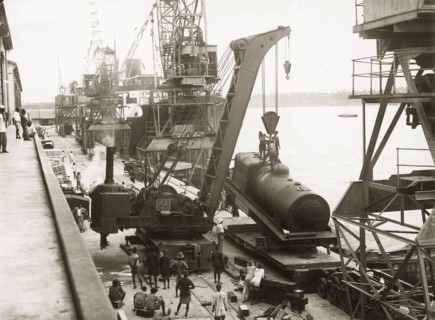 Unloading a locomotive boiler at Kilindini harbour. A railway steam crane lowers a train engine