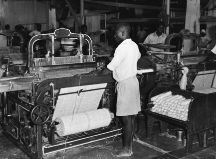 Sisal weavers. A barefoot factory worker operates a weaving machine at Sisal Products Ltd. Grown