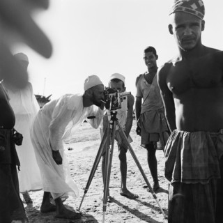 Amateur photographer. A man smoking a cigarette bends over to peer into the viewfinder of a