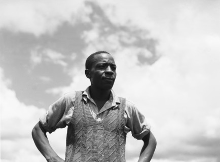 Headman Samuel. Upper body shot of Headman Samuel standing, hands on hips, wearing a shirt and a