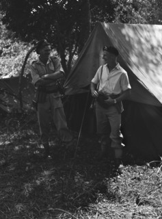 Uniformed soldiers at a KAR camp. Two armed and uniformed European soldiers share a joke at a