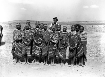 Barabaig chief with young women. A chief from the Barabaig tribe stands over a group of young