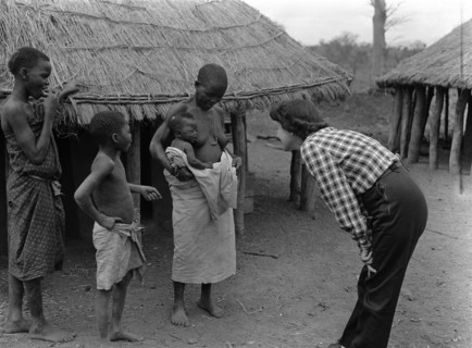 Mrs Price meets a baby. Mrs Price leans in to communicate with a baby sitting on its mother's hip.