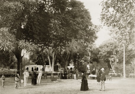 Mixed-sex tennis match. A small gathering of onlookers watches a tennis match between a group of