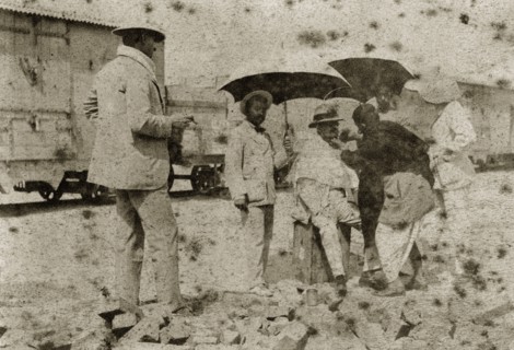A shave in the shade. A British gentlemen is shaded with parasols as he is shaved by an Indian