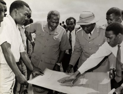 Jomo Kenyatta meets town planners. Farm planners gather around a blueprint to explain their