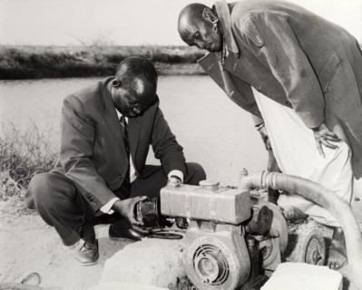 Reservoir water pump. A interested by-stander observes as a man in a suit inspects a reservoir pump