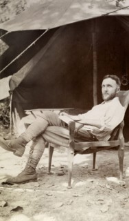 European camper. A European man relaxing in a chair outside his tent, looks up from the letter he