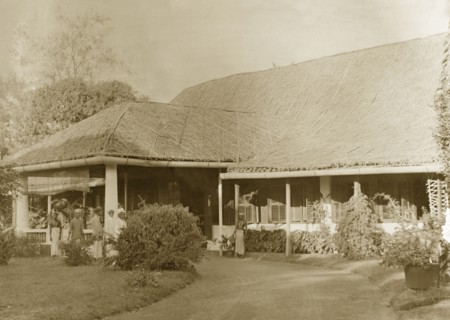 Colonial bungalow, Burma (Myanmar). Several servants stand on the driveway at the entrance to a
