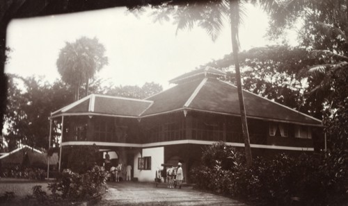 Colonial bungalow, Burma (Myanmar). Horse-drawn carriages wait in the driveway outside a large