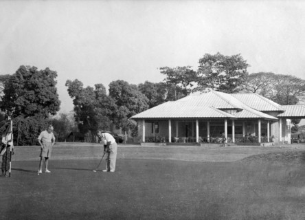 Playing golf, Rangoon. Golfers practice their putts outside the newly opened club house at the
