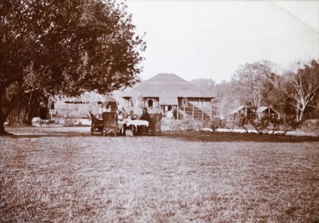 Tea party in an estate garden. Three Europeans sit at table and take tea in the garden of Mrs