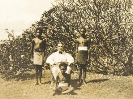 Clifford Francis poses with his servants. Outdoors portrait of Clifford Francis, a European