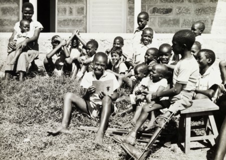 Children at a charity in Nairobi. An older boy reads a story to a group of younger children on a