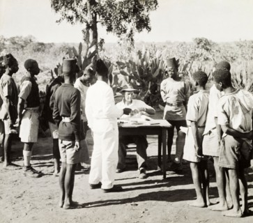 African workers collecting their pay. Young African men in Western-style clothing form a queue at a
