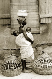 Yoruba woman with 'pickins'. A barefooted Yoruba woman wearing a headscarf carries two babies