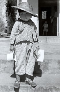 Refugee from China. A refugee boy from China stands on steps infront of an open doorway with an