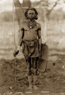 Kikuyu warrior. Full-length portrait of a Kikuyu man wearing neck ornaments and a waist cloth and
