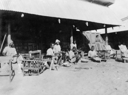 Caning chair frames. Local employees of the Kenyan Public Works Department cane wooden chair frames