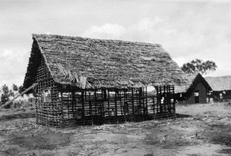 Framework for a new classroom. The timber framework and thatched roof of a classroom being built by
