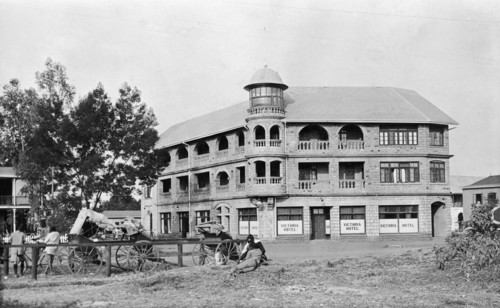 The New Stanley Hotel. Rickshaws parked outside the New Stanley Hotel on a corner of Sixth Avenue.