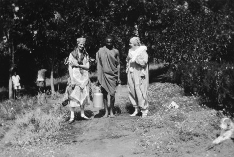 Christmas fancy dress with servant. Two European women wearing fancy dress stand either side of an