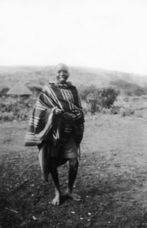 Kamba boy. Informal portrait of a smiling Kamba boy wearing a striped blanket. Kenya, circa 1927.