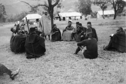 Policeman meets with Kamba elders. A Kenyan policeman sits on the ground for a meeting with a group