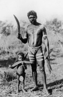 Aborigines with boomerangs. An aboriginal man holding several wooden boomerangs poses for the