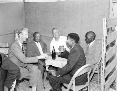 Tusker beer stand at the Royal Show. African and European visitors drink from glasses around a