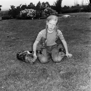 In the Russel's garden. A young girl dressed in jeans with her hair braided into two long plaits,