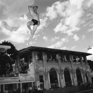 Crazy diving. A man wearing trunks at a swimming gala launches himself into the air from a diving