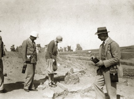 Archaeological excavation. Two European men with cameras or recording equipment accompany a woman