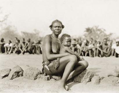 Sleeping sickness inspection. A Sudanese woman and her baby sit in front of a crowd of Sudanese