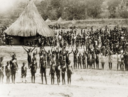 Sleeping sickness patients. A crowd of sleeping sickness patients wave at the camera from a camp