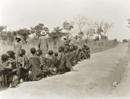 Sleeping sickness inspection. Sudanese women and babies sit in a line on a roadside awaiting