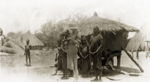 Mollie with a Golo family. A European woman captioned as 'Mollie' smiles down at the Sudanese baby