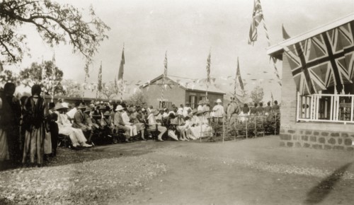 Opening of the Stack Memorial School. Two African priests stand in the shade of a tree beside a