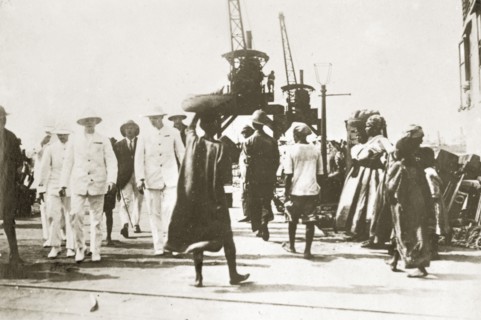 Landing stage. An African man carrying a basket of bananas on his head, weaves through a crowd at a