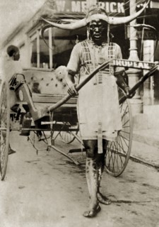 Rickshaw puller in Pietermaritzberg. A rickshaw puller stands between the shafts of his empty