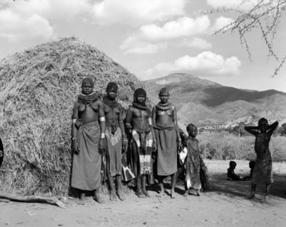 Turkana village girls. Four young Turkana women and children pictured outside a thatched village