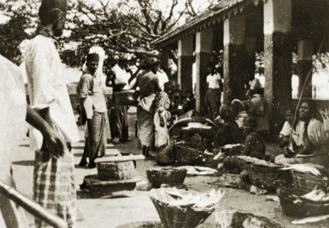 Ceylonian street market. Street traders sell goods from baskets on the floor at a busy open air
