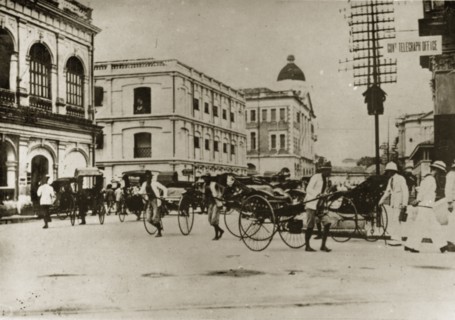 Rickshaw pullers in Penang. Barefoot rickshaw pullers compete for business at a busy crossroad in