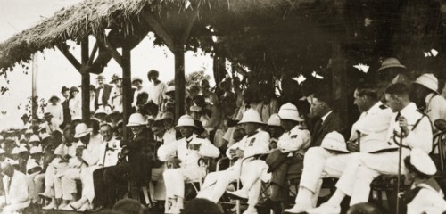 Naval officers watch a 'meke' dance. Admiral Field and other uniformed naval officers make up an