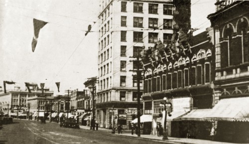 Douglas Street, Victoria. Flags hang above a quiet road lined with shopfronts identified as