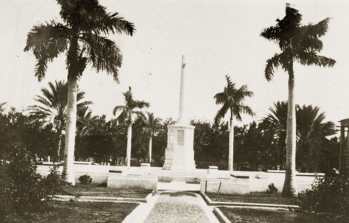 War memorial, Kingston. A war memorial stands in front of government buildings bordered by palm