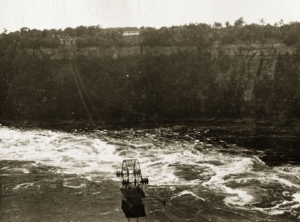 Aerial tram over Niagara Falls. An aerial tram travels on wires over the river beneath the Niagara