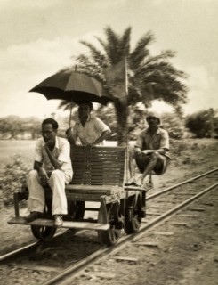 Railway hand cart. Three men sit aboard a small railway cart fitted with a wooden seat, an unusual