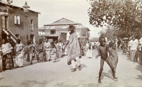 Traditional street dance. A man and children dance between long lines of women who perform a