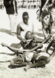 Snake charming, Tanganyika. Snake charming for an audience. The principal perfomer holds onto the